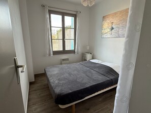 Quarto com cama, janela, mesa de cabeceira e quadro na parede.