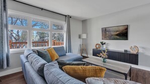 A modern living room with a grey sofa, a coffee table, and a painting on the wall.
