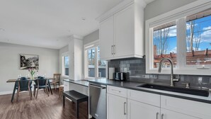 A modern kitchen with white cabinets, a black countertop, and a stainless steel dishwasher.
