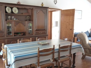 Un comedor con una amplia mesa de madera, sillas y un armario con puertas de vidrio.