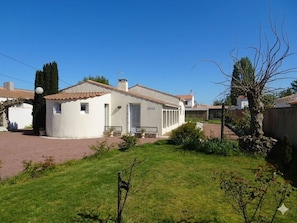 Una casa de un piso con techo de tejas, un pequeño porche y entrada pavimentada.