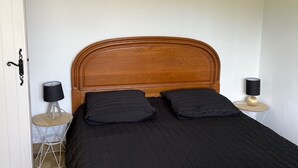 Een slaapkamer met een houten hoofdbord, twee zwarte kussens, een zwart sprei en twee nachtkastjes met lampen.