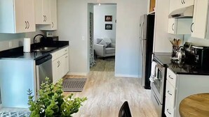 Une cuisine moderne avec des armoires blanches, un comptoir noir et un ventilateur de plafond.