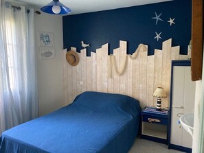Makuuhuoneessa on sänky, yöpöytä lampun kanssa, vaatekaappi ja seinä, jossa on kaupunkimaisemaa esittävä kuvio.