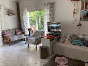 Ein Wohnzimmer mit einer Couch, einem Sessel, einem Fernseher und einem kleinen Tisch.