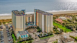 Un hotel moderno con piscina, vista a la playa y estacionamiento.