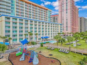A hotel with multiple floors, a playground, and a pool area.