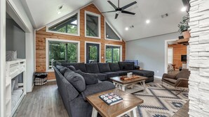 Ein geräumiges Wohnzimmer mit einer großen Eckcouch, einem Couchtisch und einem Deckenventilator.