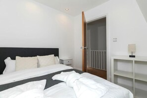 A hotel room with a bed, a nightstand, a desk, and a door leading to a balcony.