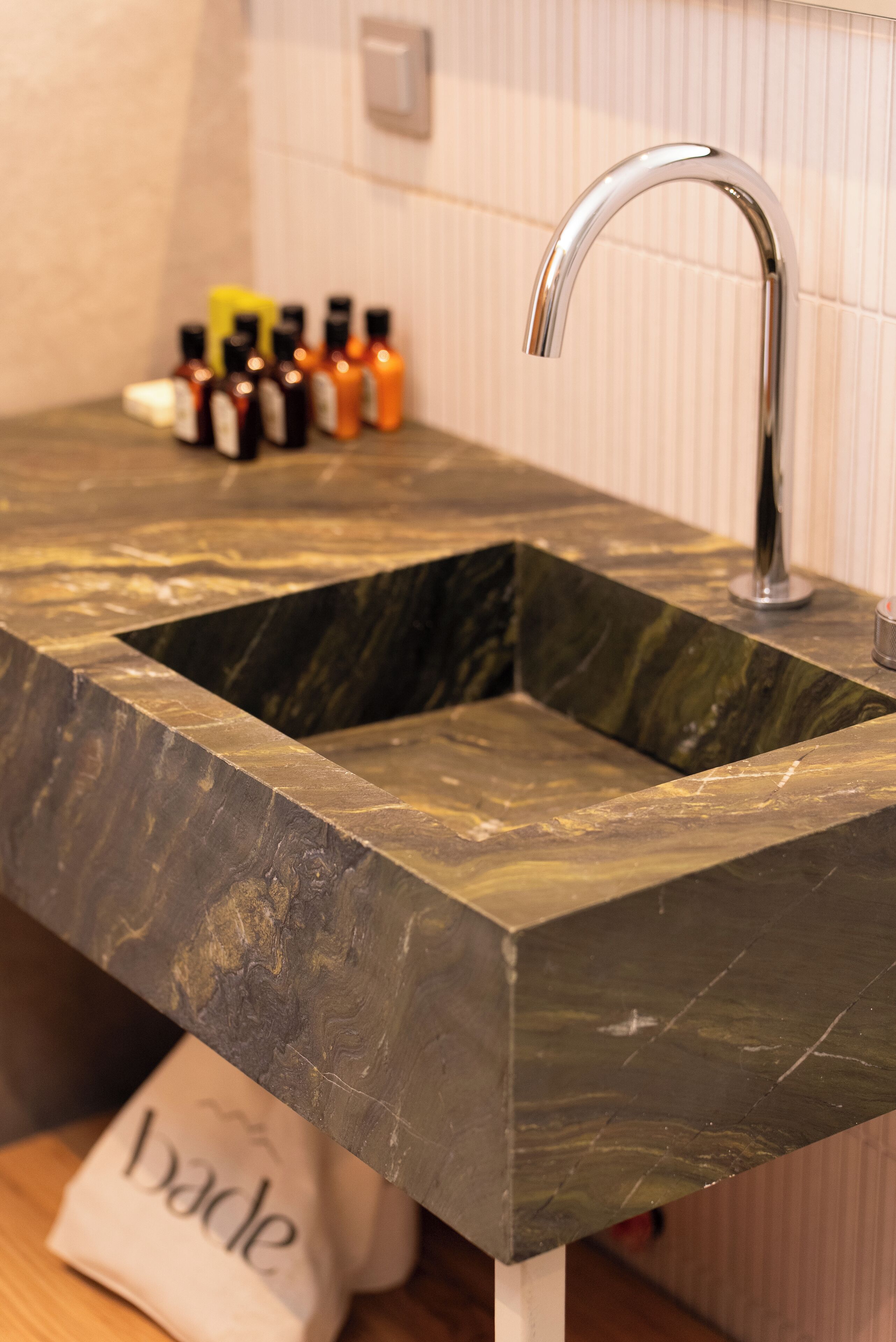 A bathroom sink with a modern design, a faucet, and a set of toiletries on the countertop.