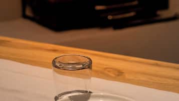 Disposição de mesa para refeições, com prato, garfo e copo, e uma lareira ao fundo.