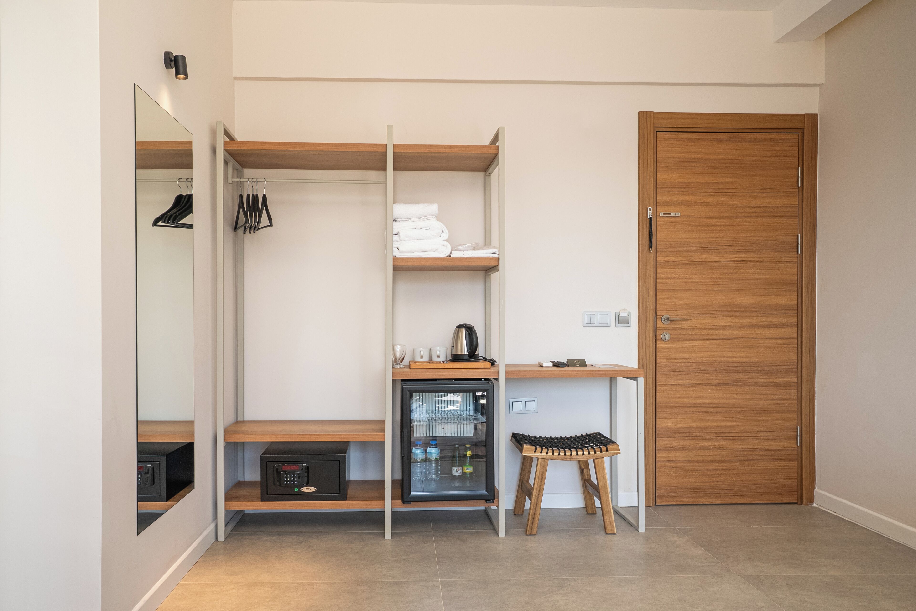 A compact room with a wardrobe, a small kitchenette, and a mirror.