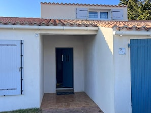A building with a tiled roof, a blue door, and a number '2' sign.