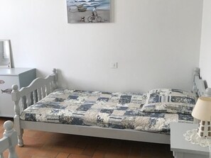 Un dormitorio con cama, mesita de noche, lámpara y un cuadro en la pared.