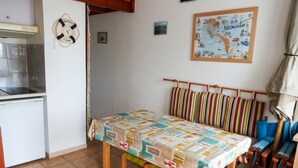 A small kitchen with a refrigerator, a clock, and a map on the wall.
