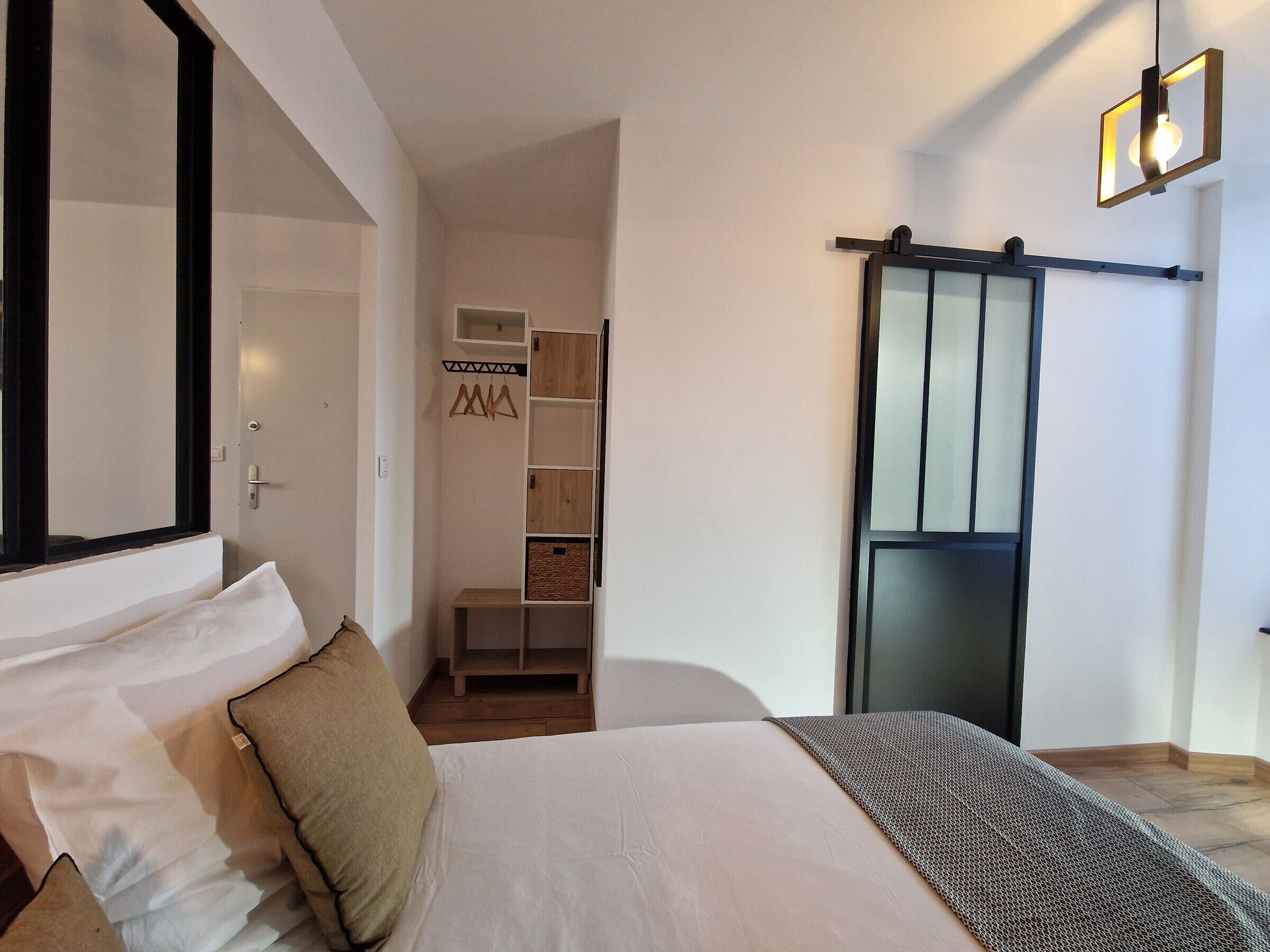Ein Schlafzimmer mit einem Bett, einem Kleiderschrank und einer Hängeleuchte.