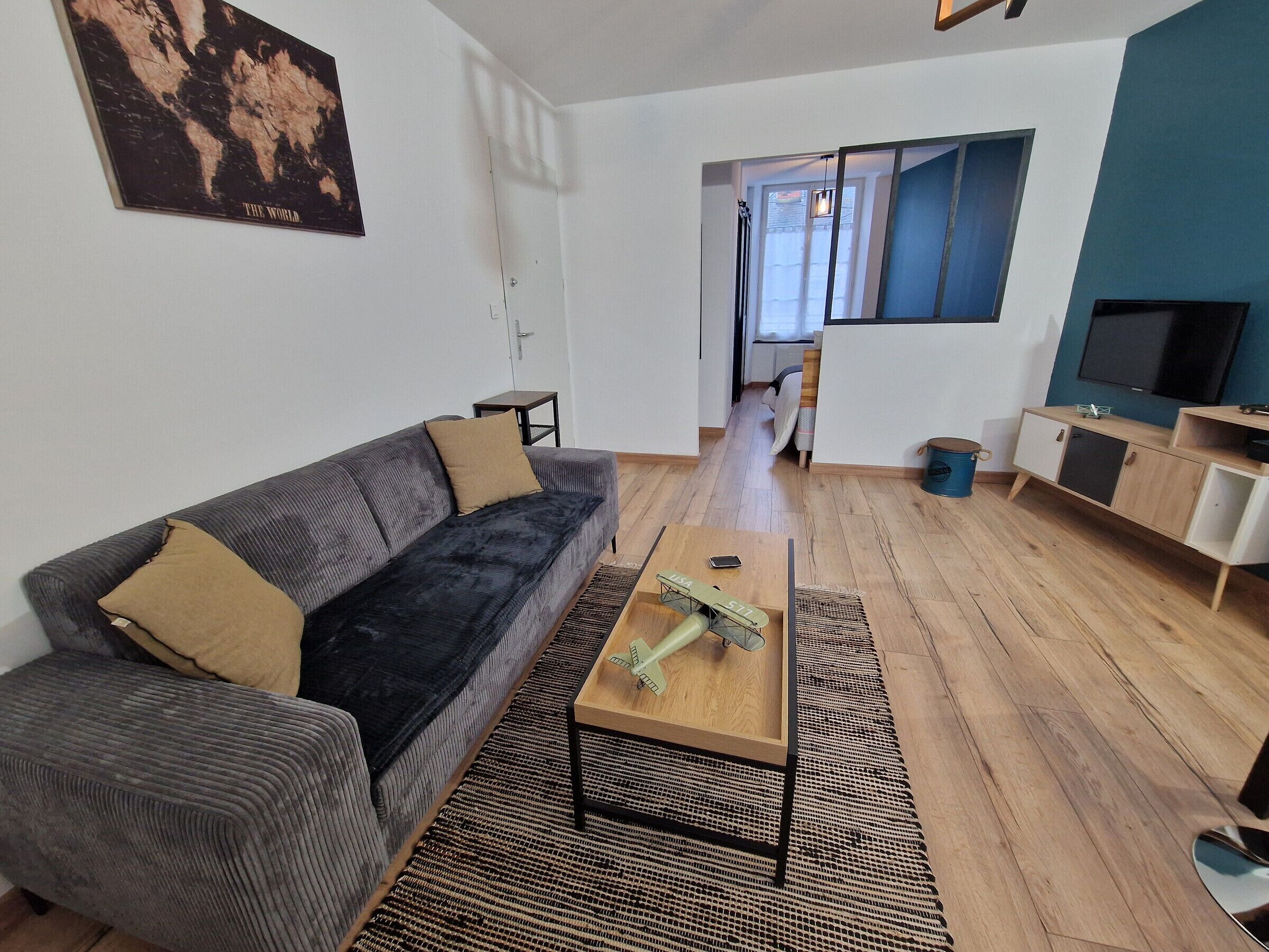 A modern living room with a grey sofa, a coffee table, and a television.