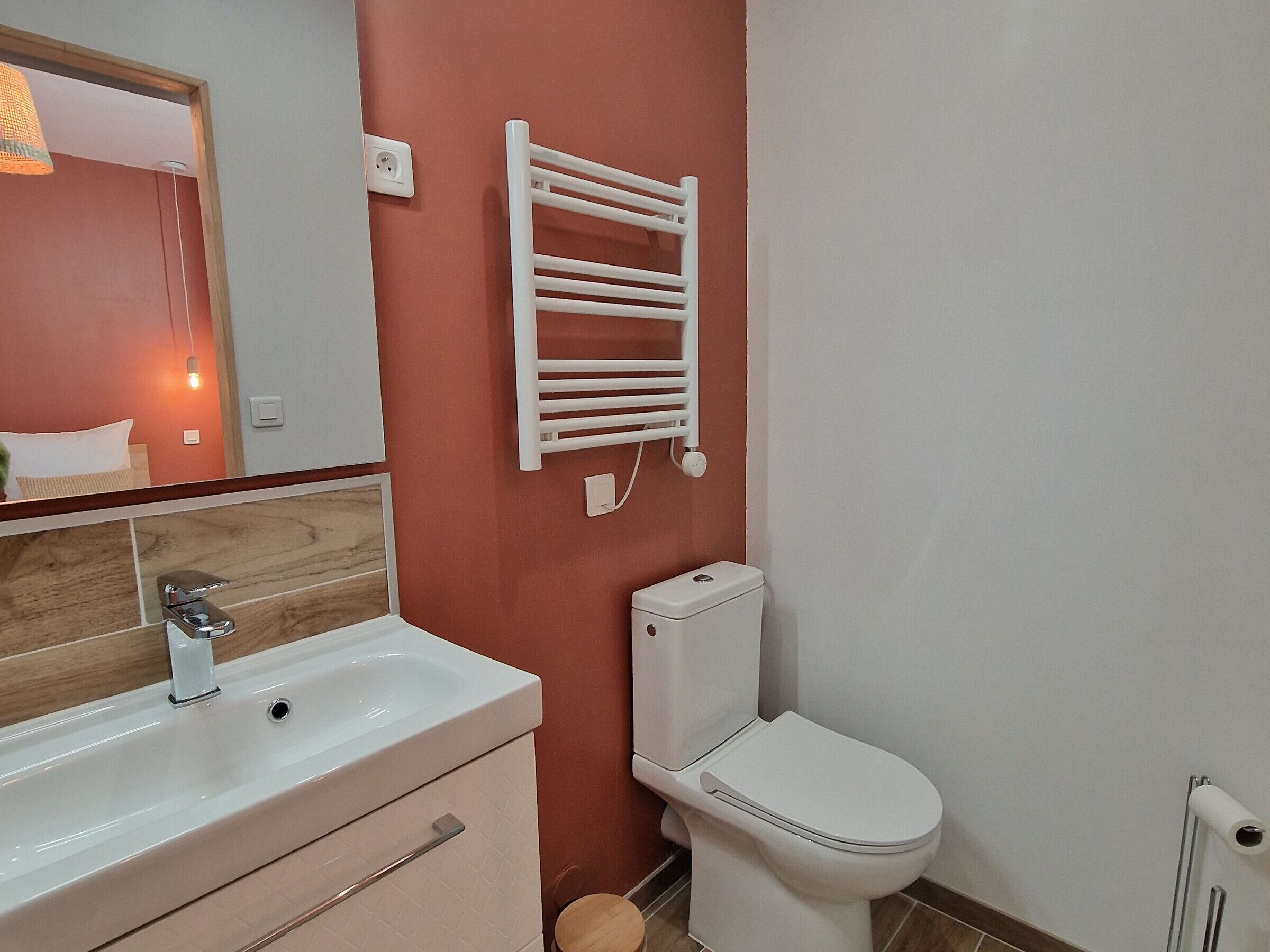 Een badkamer met een wit wastafel, spiegel en toilet.