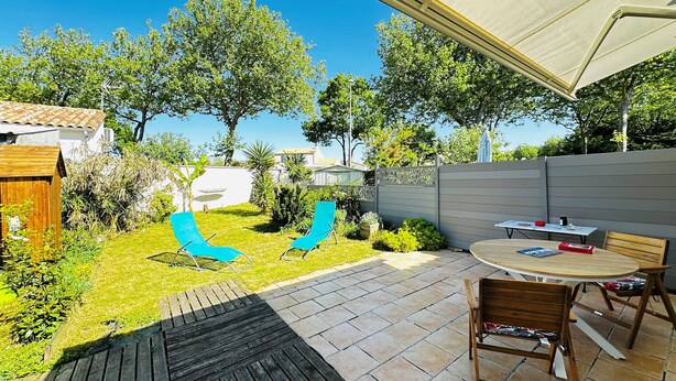 Un patio con mesa y sillas, un parque infantil y una zona cubierta.
