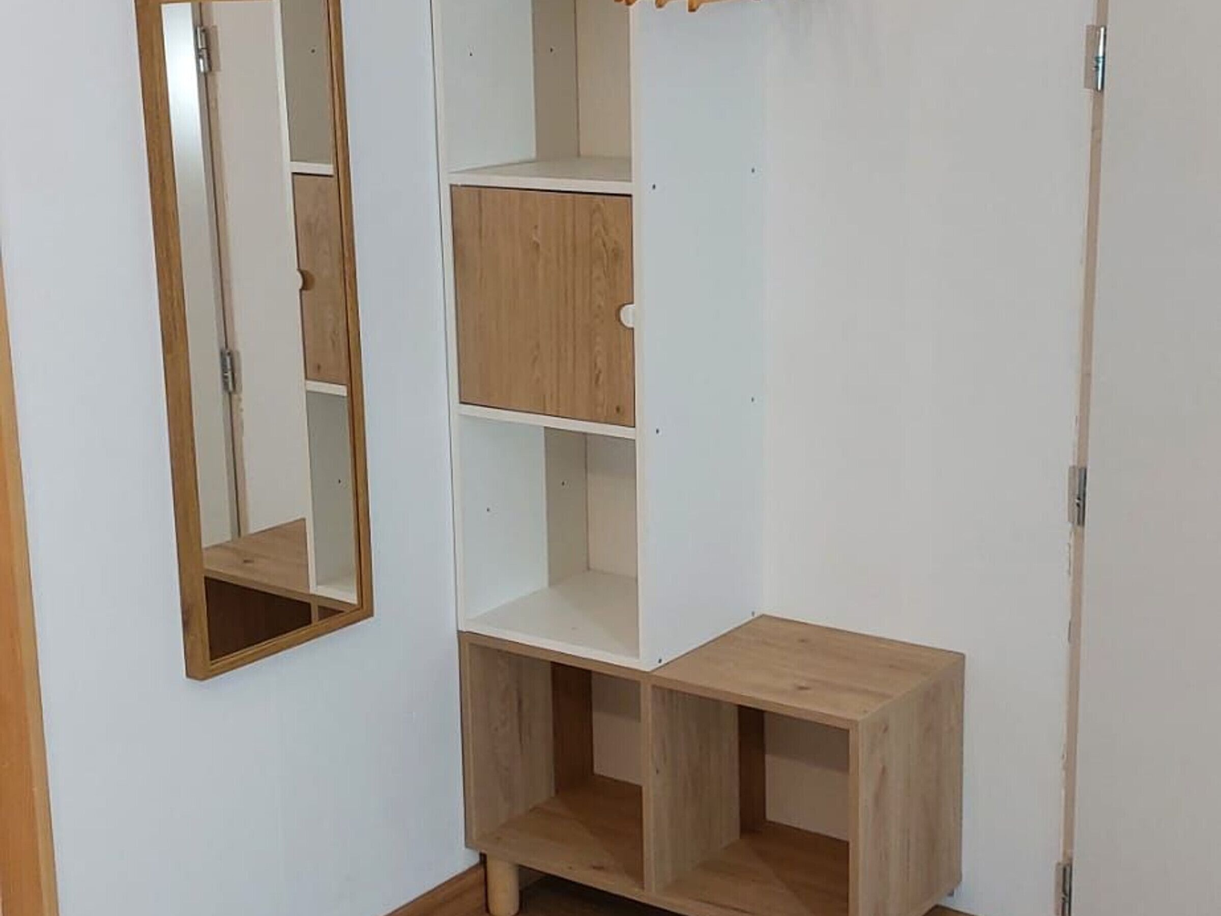 A corner wardrobe with multiple shelves and a mirror.