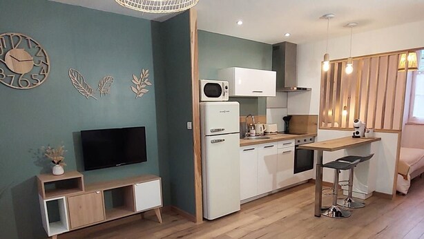Une cuisine moderne équipée d’un four à micro-ondes, d’un four et d’un évier. Un petit coin repas avec une table et des chaises est également disponible.