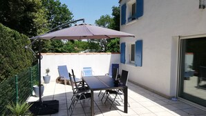 A patio with a table and chairs, a large umbrella, and a potted plant. - Vaux-sur-Mer: 2-Bed Villa for 5, 450m to Beach, Parking, AirCon (Vaux-sur-Mer)