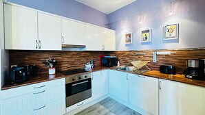A modern kitchen with white cabinets, a wooden countertop, a stainless steel oven, and a microwave. - Charming house 200m from beach for 5 people (Fouras)