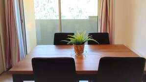 Un coin repas avec une table et des chaises, une plante en pot et une vue par la fenêtre.