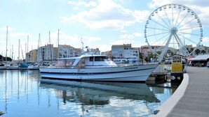 A marina with boats docked, a Ferris wheel, and buildings in the background. - 2-room apt with parking, pool, sleeps 4, Cap d'Agde (Cap d'Agde)