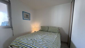 A small, neatly arranged bedroom with a single bed, a bedside lamp, and a framed picture on the wall. - 2-room apt with parking, pool, sleeps 4, Cap d'Agde (Cap d'Agde)