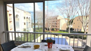 A balcony with a table set for two, overlooking a residential area with buildings and trees. - 2-room apt with parking, pool, sleeps 4, Cap d'Agde (Cap d'Agde)