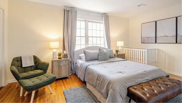 A bedroom with a bed, a chair, a nightstand, a lamp, and a window with curtains. - 3BR Stay for Crews & Families (Elizabeth)