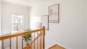 A staircase with wooden railings and a view of a building outside. - 3BR Stay for Crews & Families (Elizabeth)