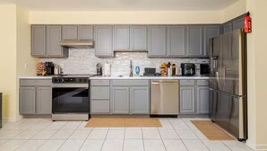 A modern kitchen with grey cabinets, stainless steel appliances, and a tiled floor. - 3BR Stay for Crews & Families (Elizabeth)