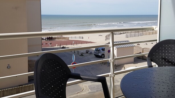 Ein Balkon mit Blick auf den Strand, ein geparktes Auto und ein Verbotsschild.