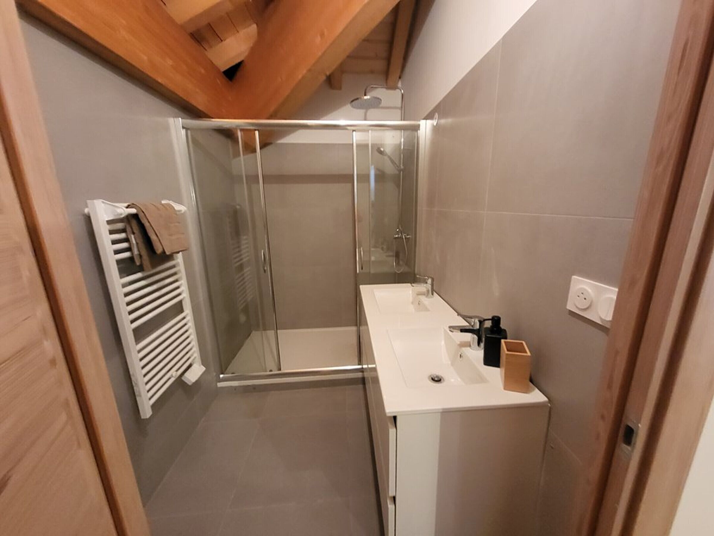 Une salle de bain moderne avec une douche à parois de verre, un lavabo blanc et un porte-serviettes.