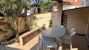 An outdoor patio with a table and chairs, surrounded by plants and a decorative fence. - Comfortable villa near sea for 6 people, private garden (Argelès-sur-Mer)