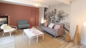 A cozy living room with a white sofa, a blue armchair, and a white coffee table. There is a large tapestry on the wall and a woven vase on the floor. - Family cottage between Angers and Saumur (Blaison-Saint-Sulpice)