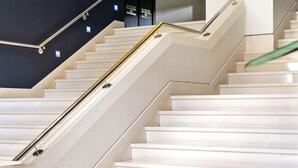A modern staircase with white steps and a metal handrail.