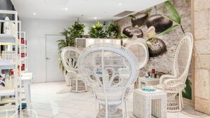 A spa area with white wicker chairs, a reception desk, and a wall mural.