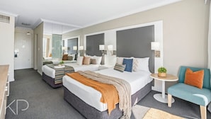 A modern hotel room with two beds, a sitting area, and a small table with a plant.