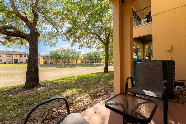 A patio area with outdoor seating, a tree, and a view of a courtyard with buildings in the background.