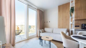A modern living room with a sofa, a round coffee table, and a dining area with a table and chairs. - Rynek Wrocław Luminous Apartment (Wroclaw)