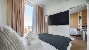 A hotel room with a bed, a TV mounted on the wall, a desk, and a chair. - Rynek Wrocław Luminous Apartment (Wroclaw)
