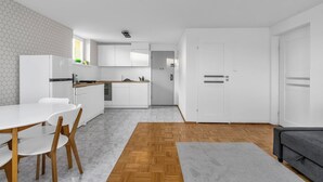 A modern kitchen with white cabinets, a wooden dining table, and chairs. - Mokotów Serene Apartment (Warszawa)