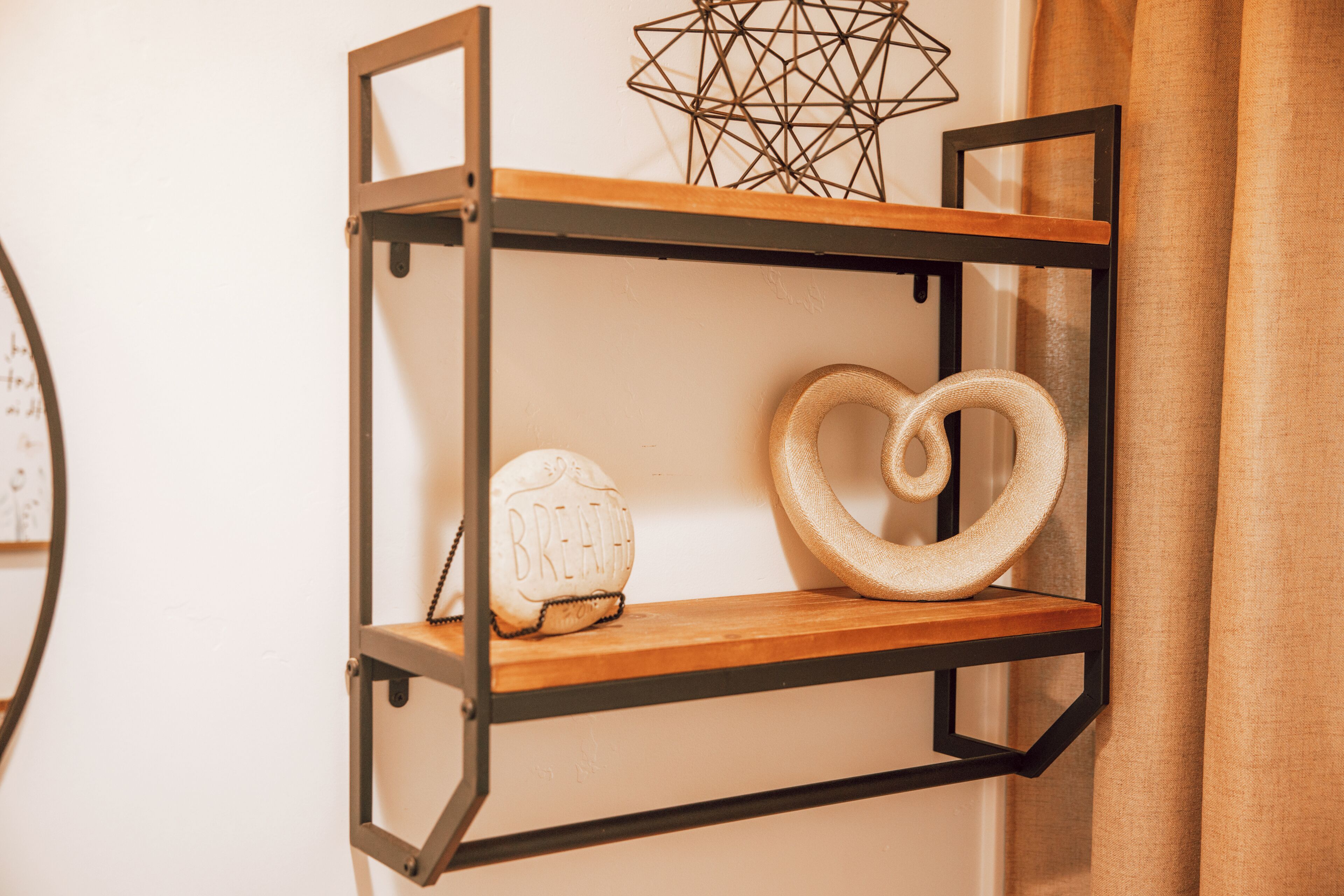 A wall-mounted shelf with a geometric light fixture and a heart-shaped decoration.