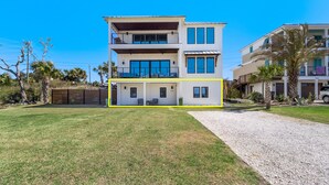 A two-story house with a balcony on the upper floor, a covered patio on the ground floor, and a gravel driveway. - "Salt Therapy" offers gulf views, 100 steps to beach, modern 2BD/2BA, single level! (Port Saint Joe)