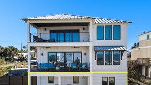 A two-story house with a balcony, large windows, and a garage. - "Salt Therapy" offers gulf views, 100 steps to beach, modern 2BD/2BA, single level! (Port Saint Joe)