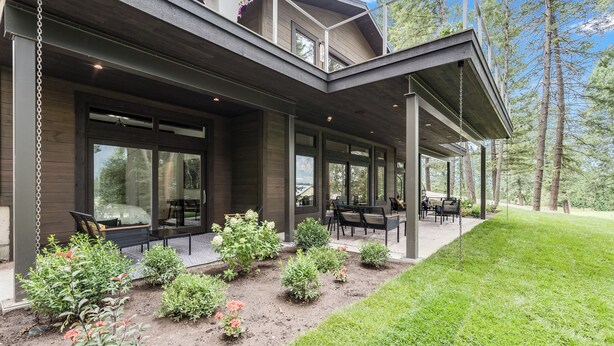 Une maison moderne dotée d’un patio couvert, d’un espace salon extérieur et d’un jardin bien entretenu.