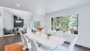 Un espace repas moderne avec une table blanche, des chaises et une cheminée.